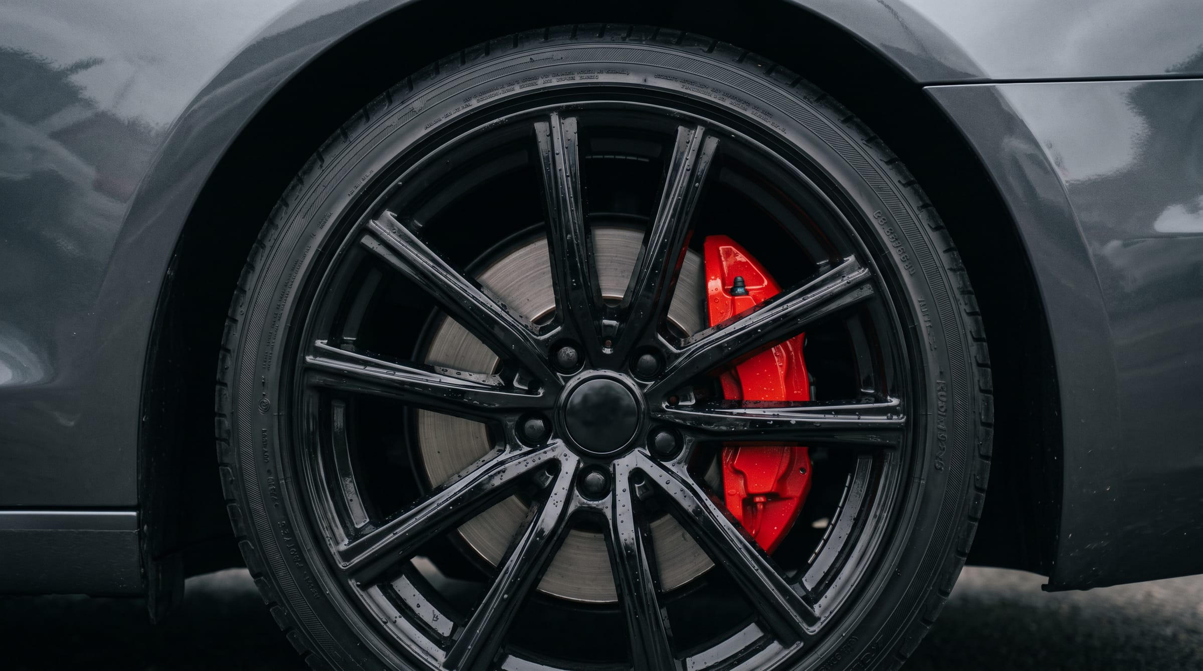 Glanzende velg met gecoate remklauw en waterdruppels na detailing door SHAR de Detailer