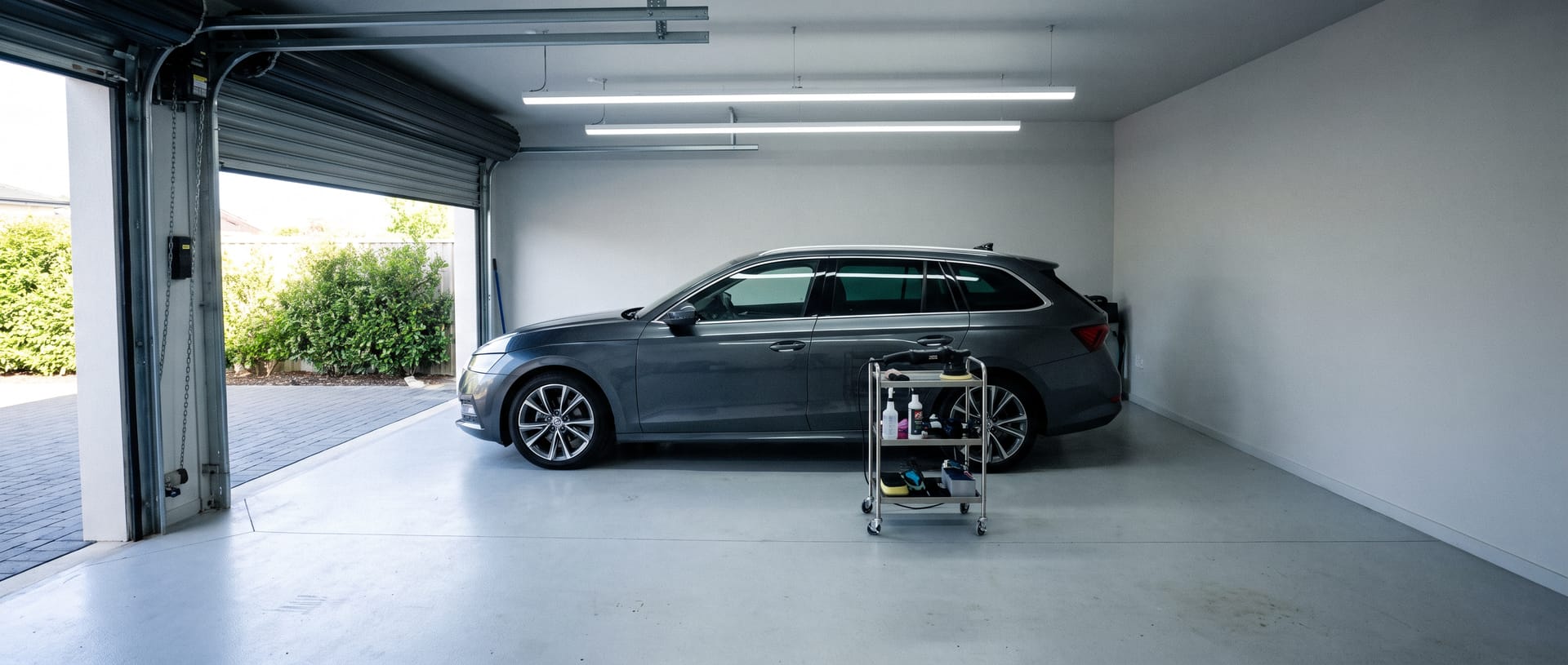 Auto onder een ledlichtbalk in een nette garagebox, polijstmachine op een kar
